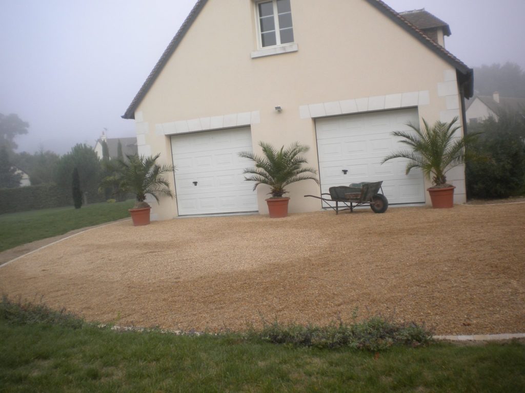 Aménagement d'une allée en gravier devant garages de maison