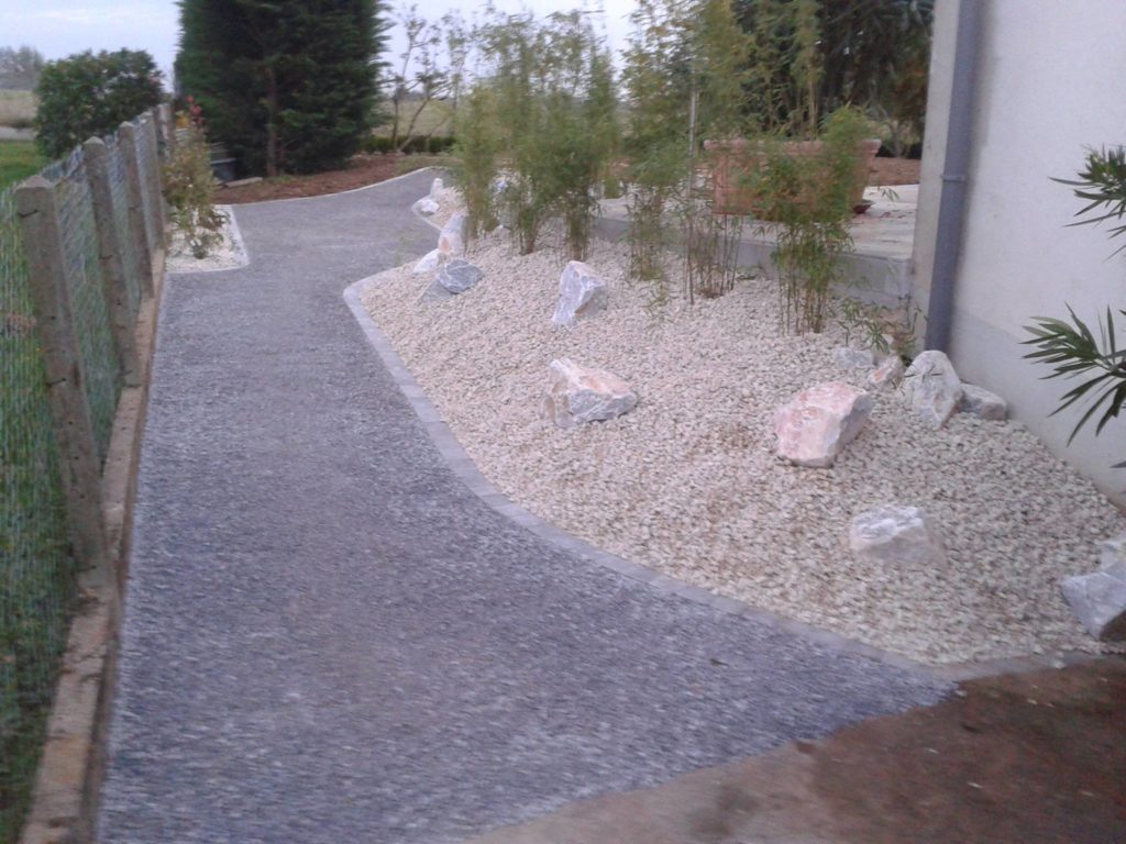 Aménagement d'une allée bétonnée avec des graviers et rochers en décoration par Entre Pierres et Vert