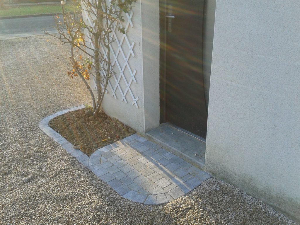 Aménagement d'une allée devant porte d'entrée à l'aide de pavés et graviers par Entre Pierres et Vert