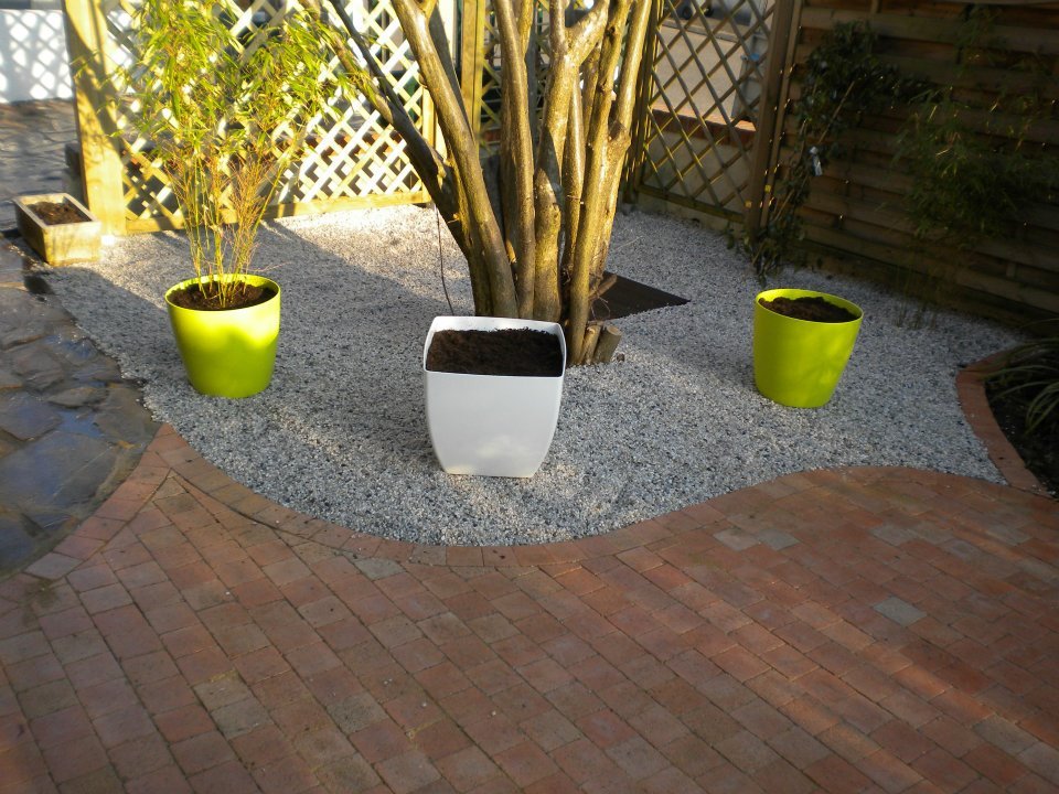 Création d'une terrasse et aménagement paysager à l'aide de graviers et plantes en pot par Entre Pierres et Vert